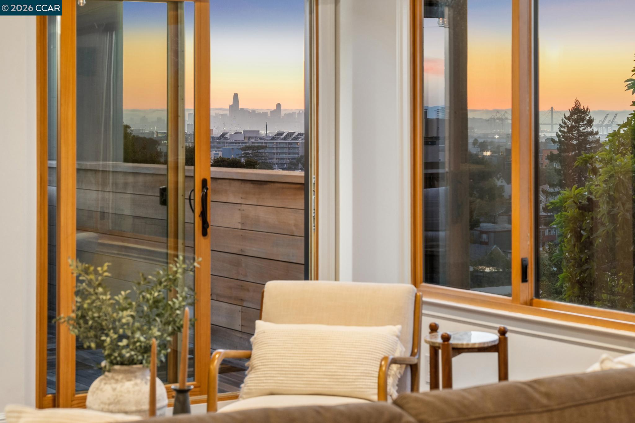 Living area with balcony doors and sunset views of the city skyline.