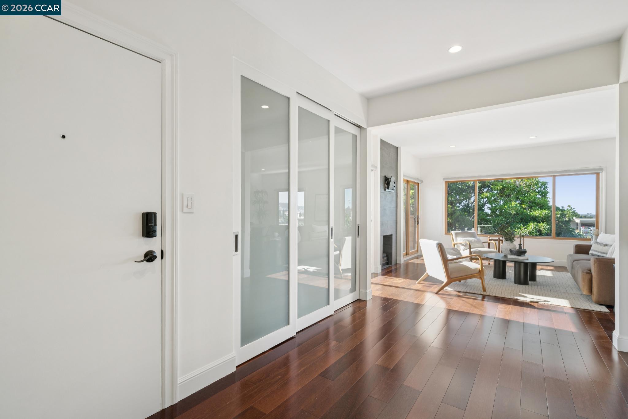 Condo entry opening to a bright living room with hardwood floors, glass doors, and large windows.