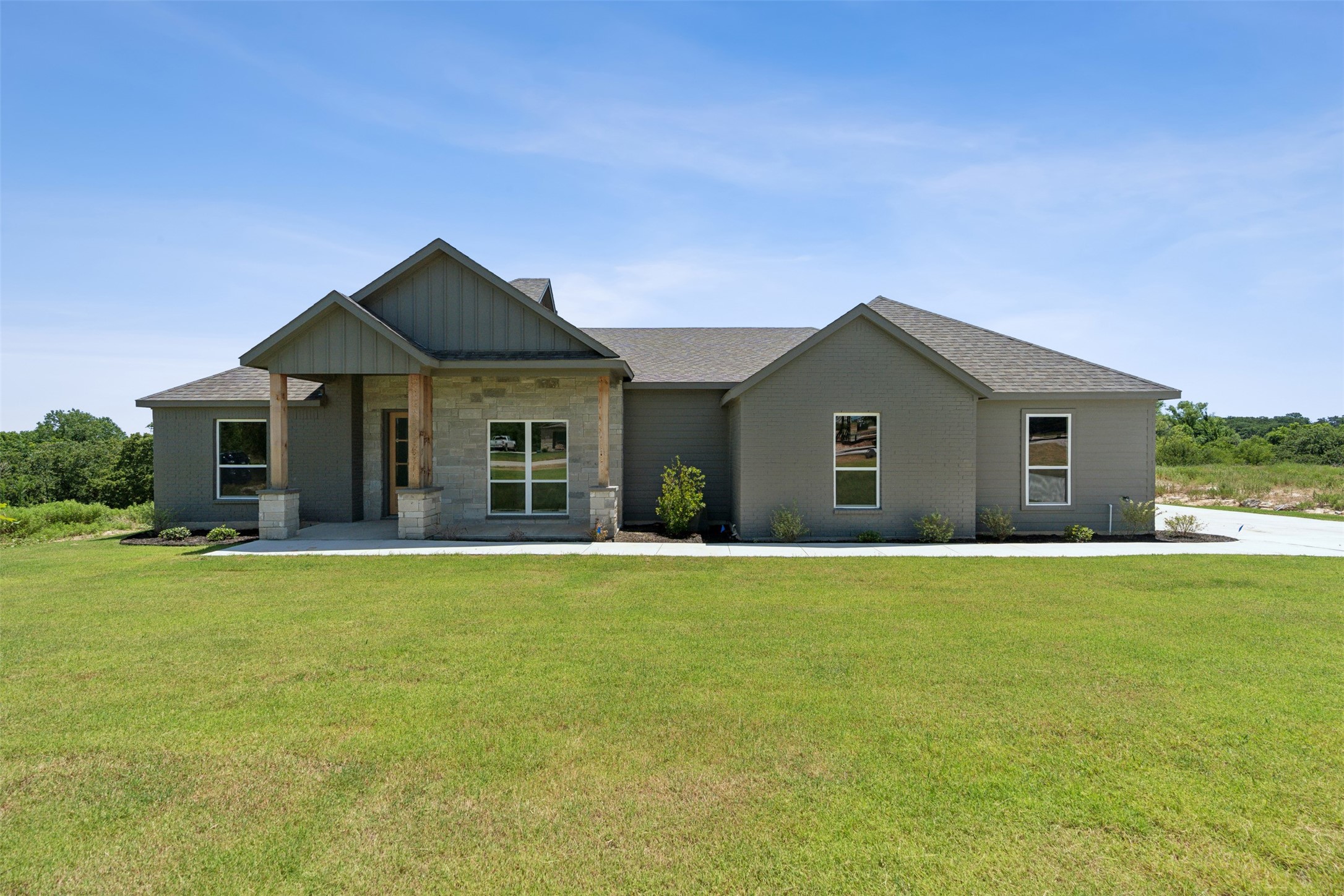 Single-story gray home with stone entry accents and a broad front lawn.