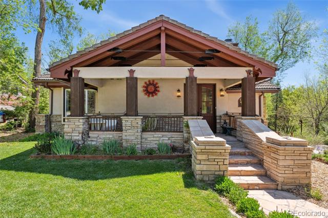 House with a broad gabled porch, stone pillars, and a green front lawn.