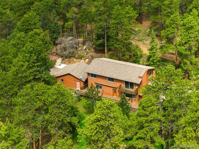 Aerial view of a wood-sided home surrounded by dense trees.