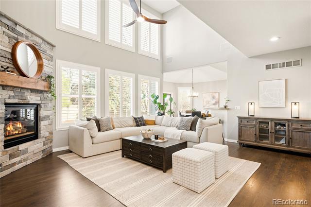Living room with a stone fireplace, tall shuttered windows, and a cream sectional.
