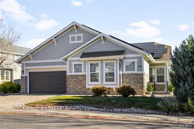 Gray house with stone accents, solar panels, and a dark attached garage.