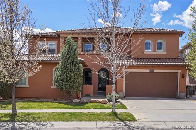 Two-story stucco home with a tiled roof, arched entry, and attached garage.