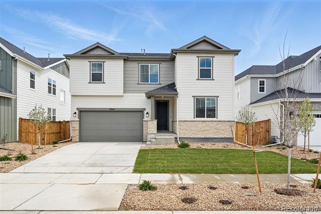 Two-story home with light siding, gray garage door, stone accents, and a small front lawn.