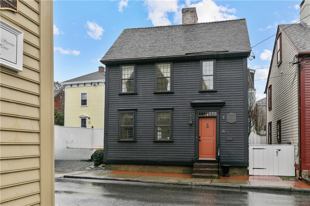 Dark gray two-story house with a steep roof and coral-colored front door.