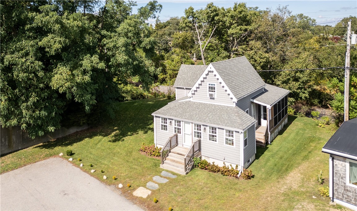 Gray two-story house with white trim, front steps, and a screened porch, surrounded by lawn and trees.