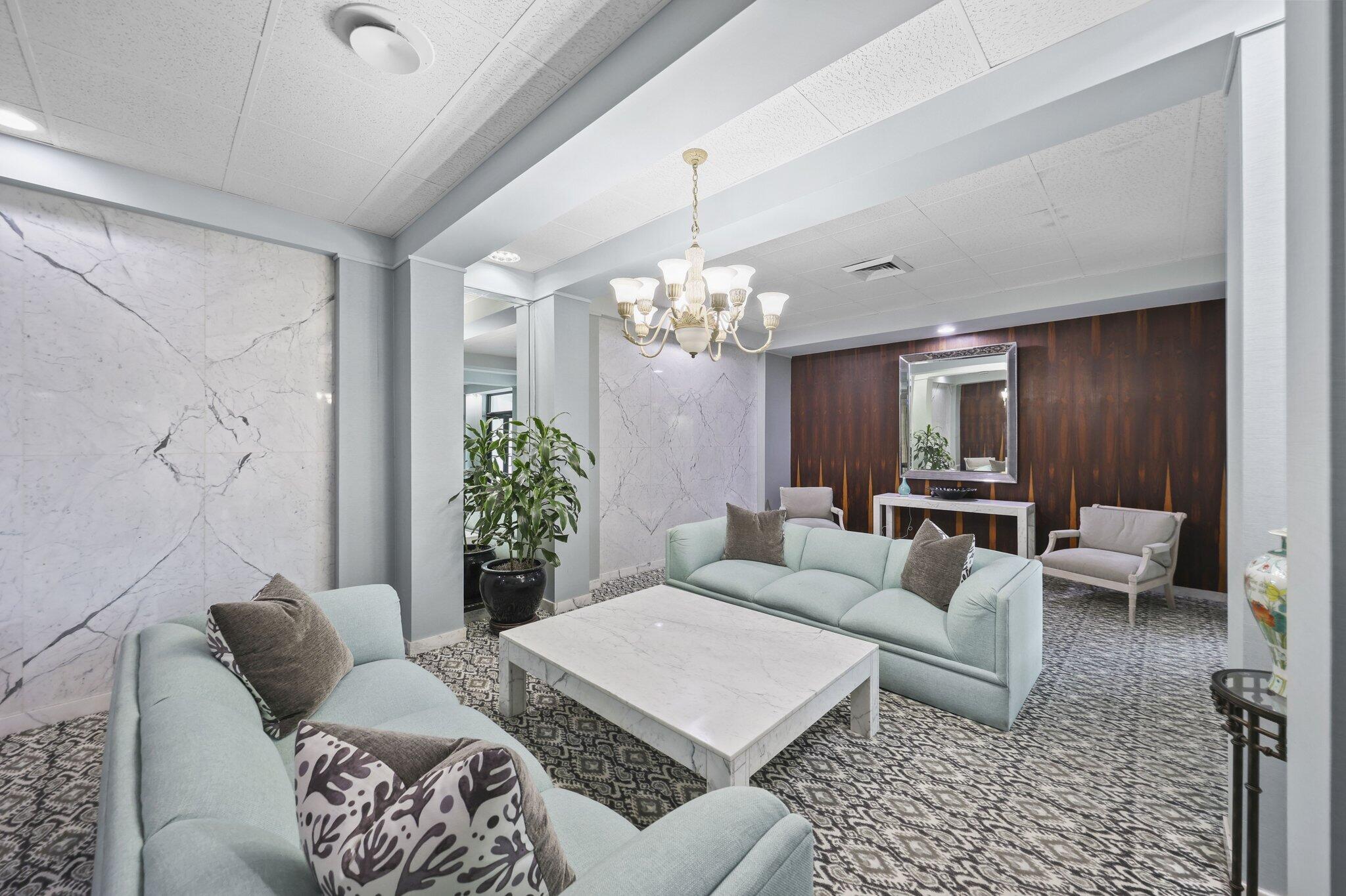 Condo lounge with pale blue sofas, marble walls, and a dark wood accent wall.