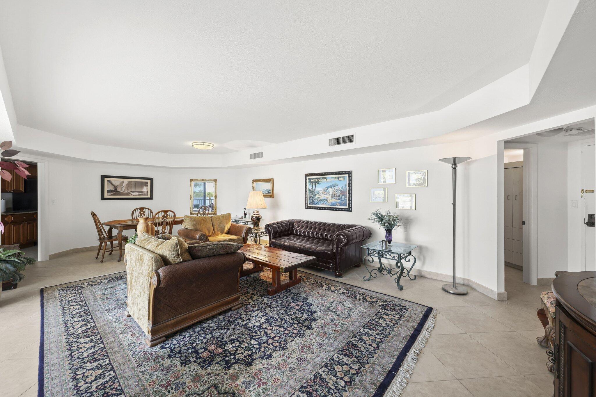 Furnished living room with a large patterned rug, leather sofas, and an adjoining dining area.