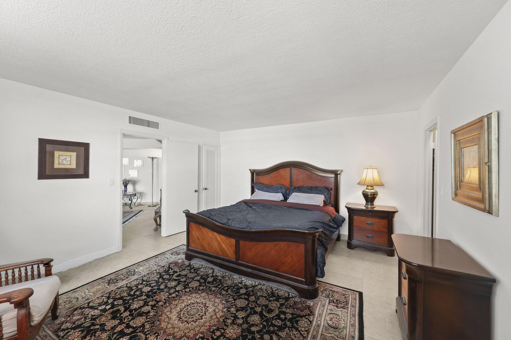 Furnished bedroom with a dark wood king bed and an ornate patterned rug.