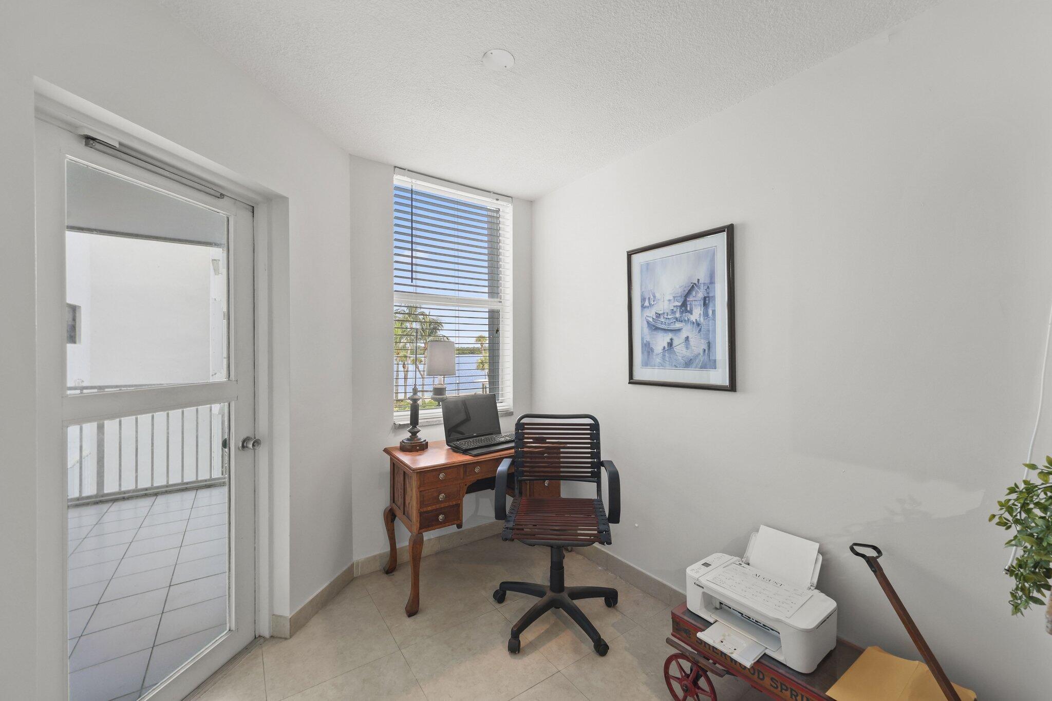 Furnished home office with a wooden desk and a window overlooking water.