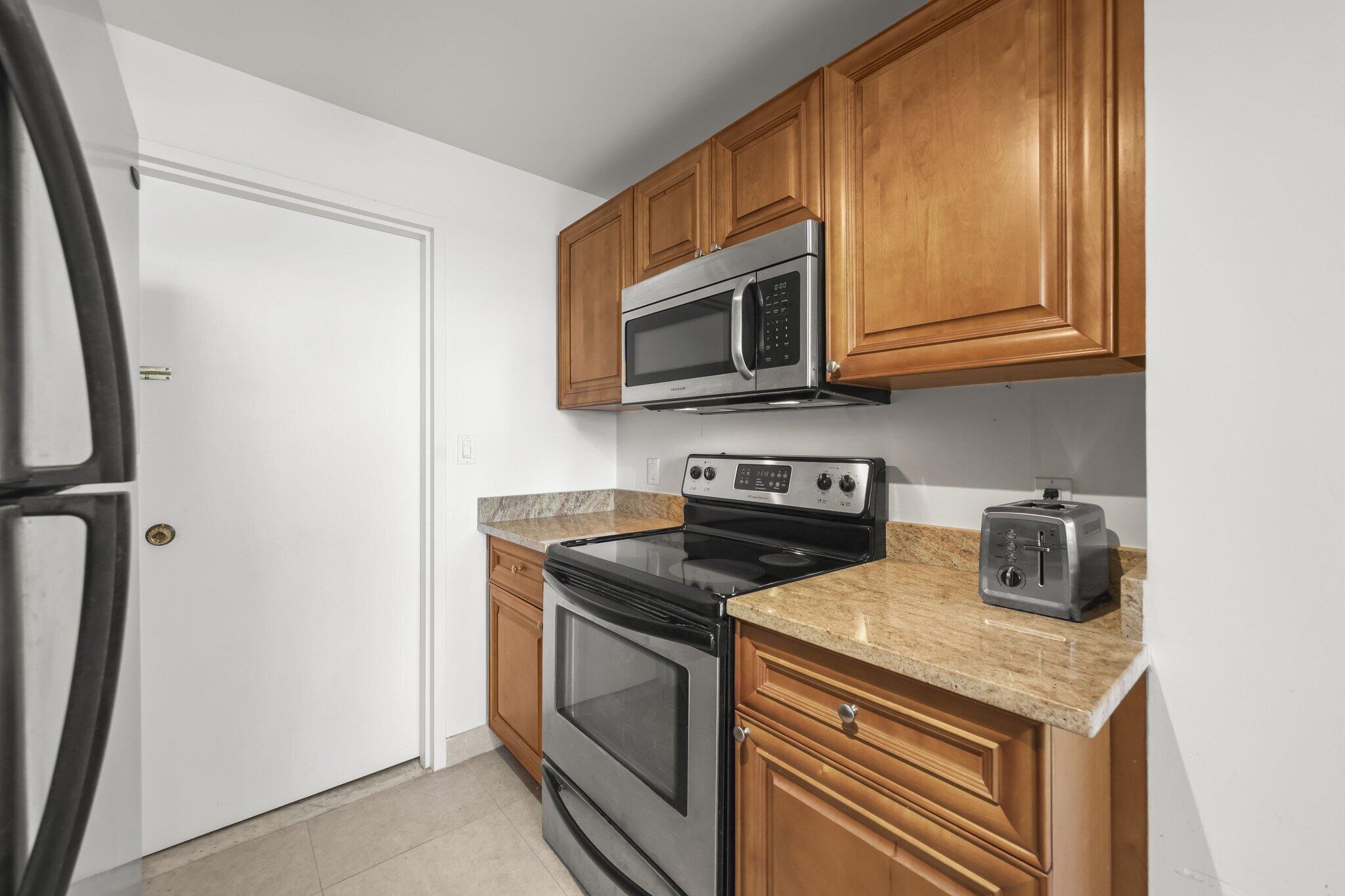 Kitchen with warm wood cabinets, granite countertops, and stainless steel appliances.
