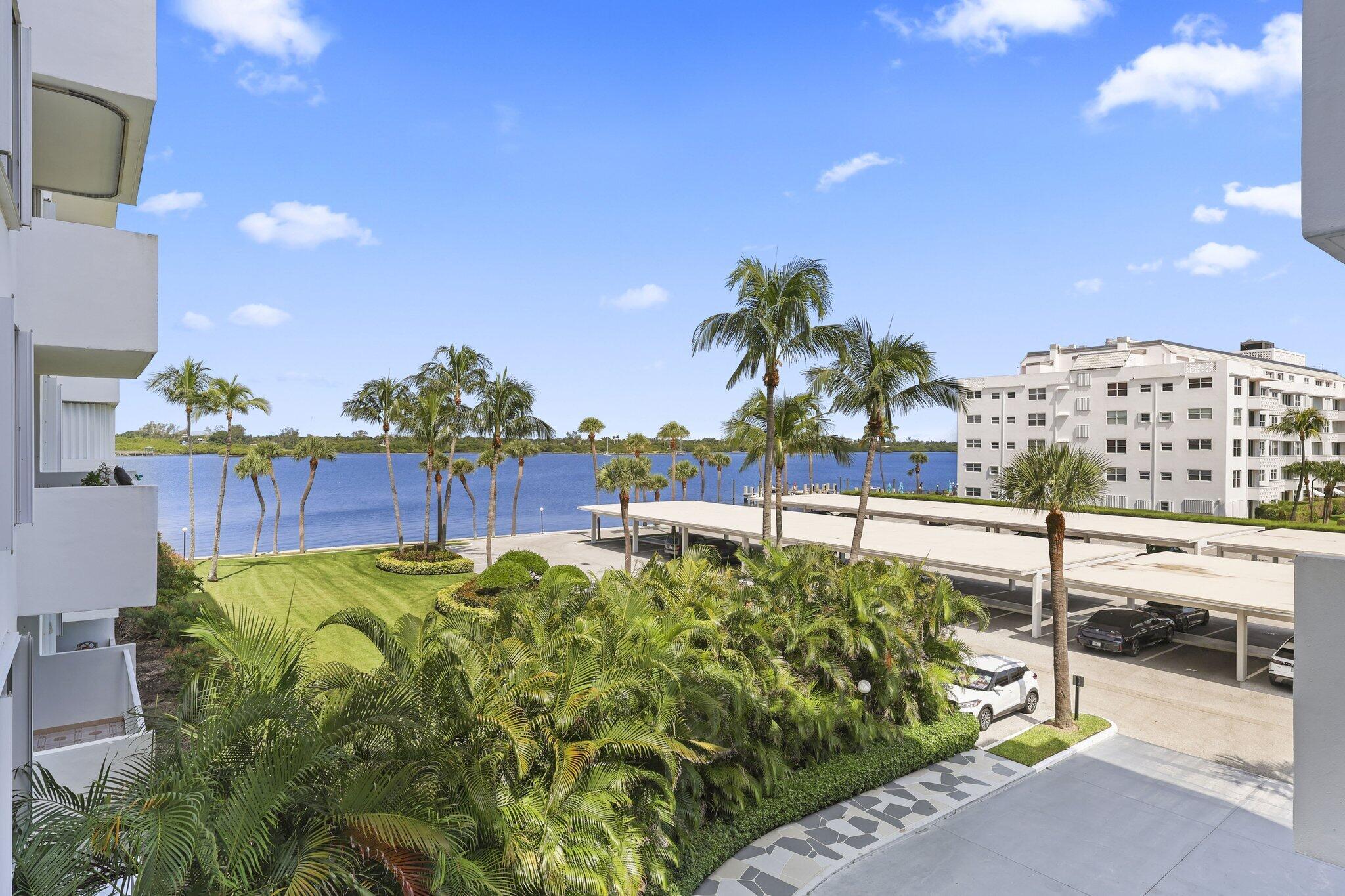 Condominium grounds overlooking the water, with palm trees, landscaped lawn, and covered parking.