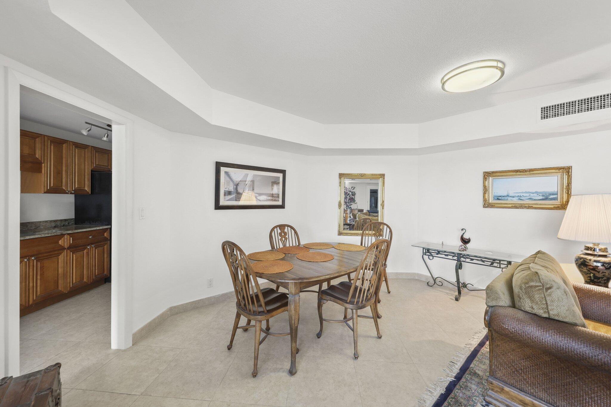 Dining area with a wooden table and chairs beside a kitchen with wood cabinets.