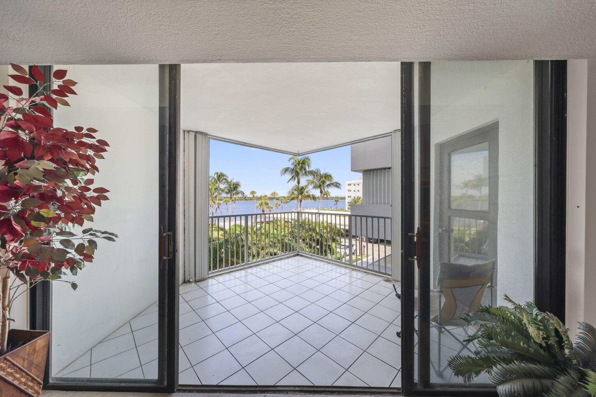 Tiled corner balcony with a water view framed by palm trees.