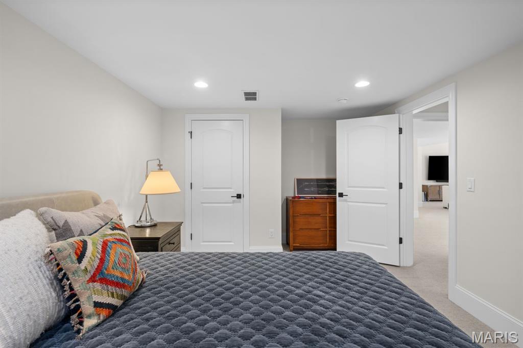 Bedroom with a gray quilted bed, colorful accent pillow, and wooden dresser.