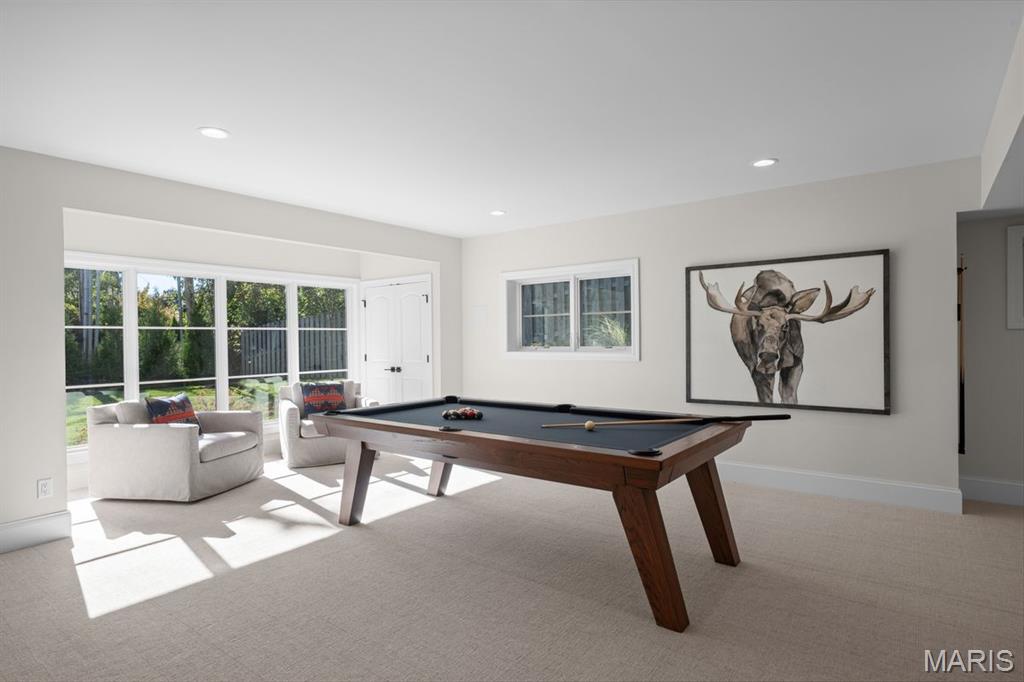 Game room with a pool table, large windows, and two chairs.
