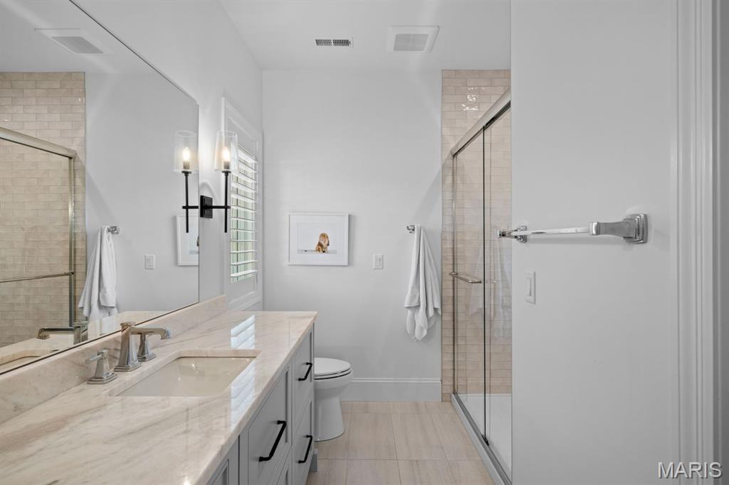 Bathroom with a long double-sink vanity and a glass-enclosed tiled shower.