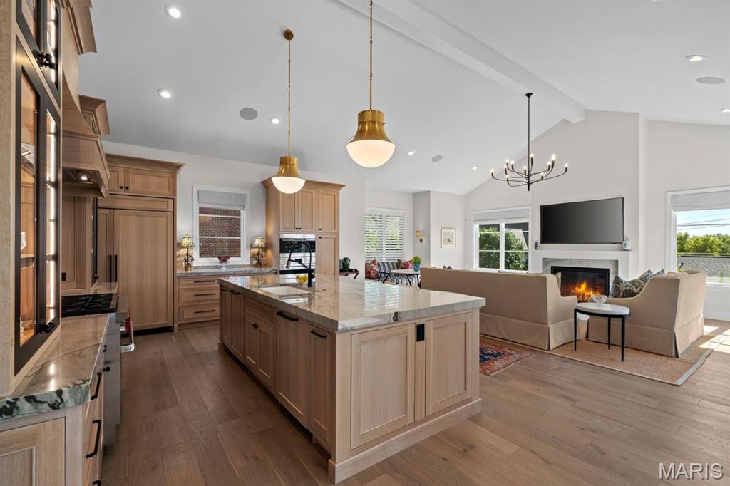 Open-plan kitchen with a large island and adjoining living room with a fireplace.