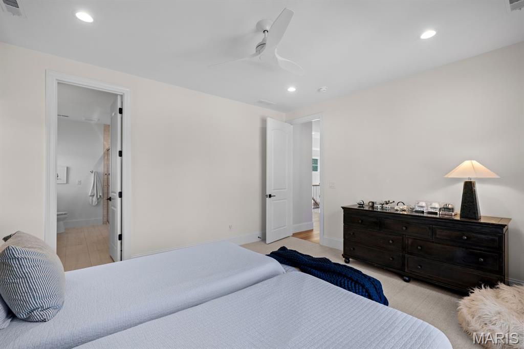 Bedroom with two neatly made beds, a dark dresser, and an open bathroom doorway.