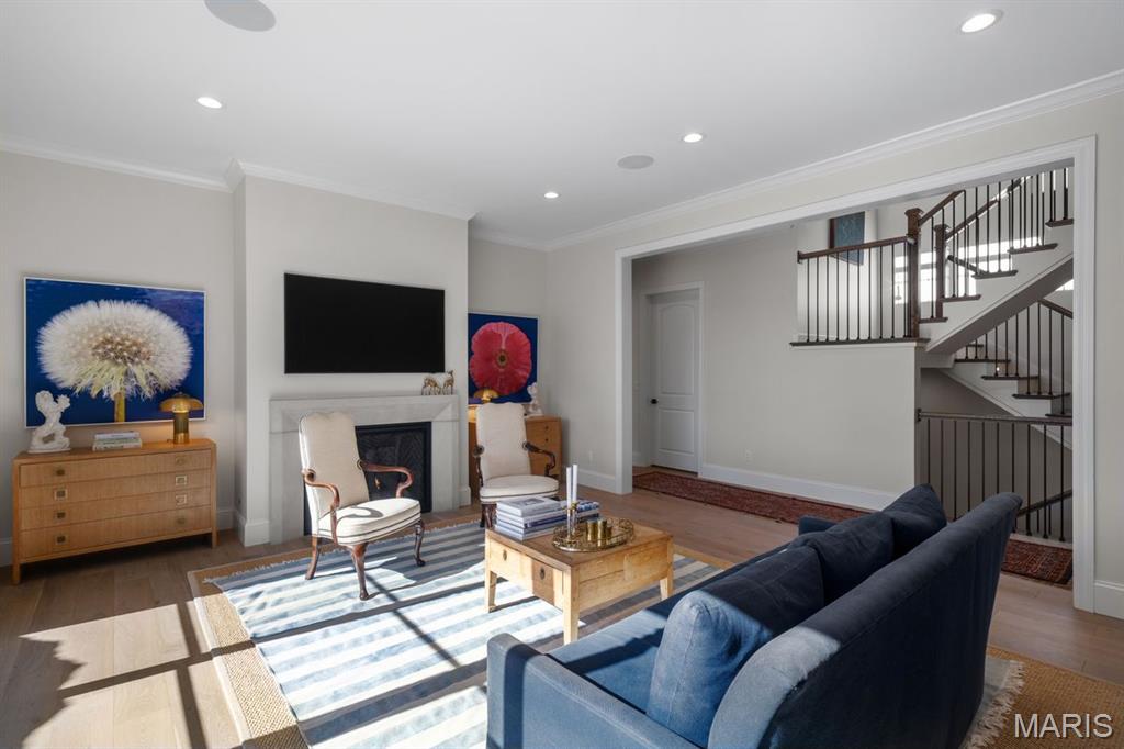 Furnished living room with a fireplace, blue sofa, striped rug, and open staircase.