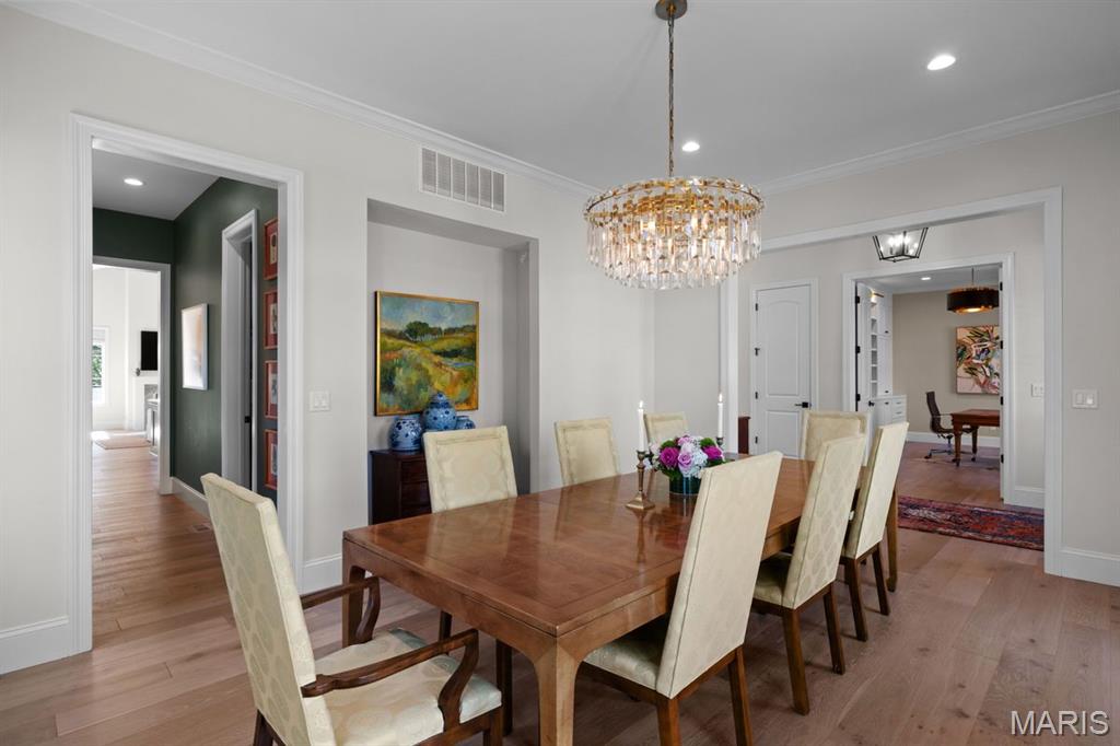 Dining room with a wooden table, cream chairs, and a crystal chandelier.