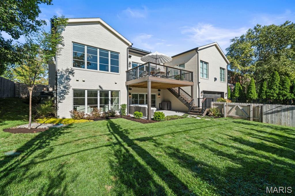 Rear exterior of a two-story brick home with an elevated deck and broad lawn.