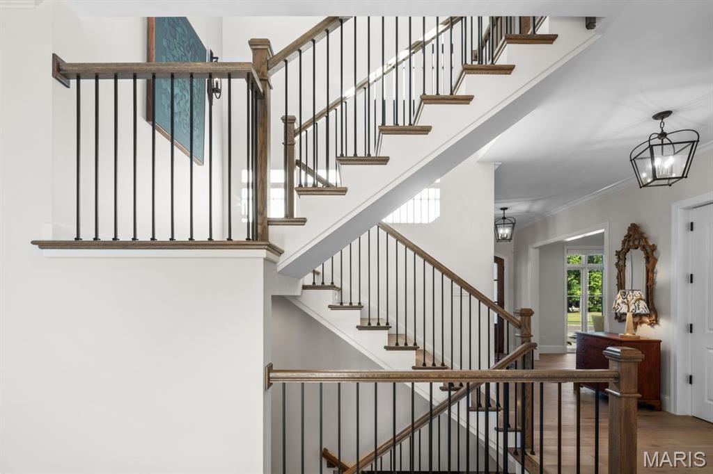 Foyer with a multi-level staircase, dark metal balusters, wood handrails, and hardwood floors.