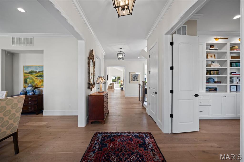 Bright entry hall with hardwood floors, built-in bookcases, and an open doorway to living spaces.