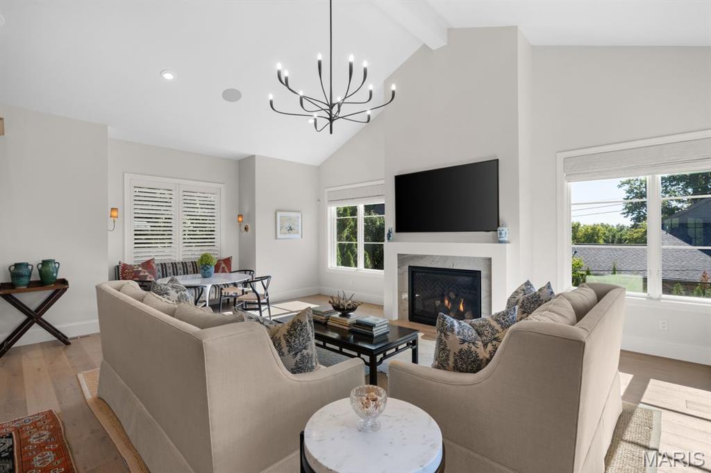 Living room with neutral sofas, a fireplace, wall-mounted television, and large windows.