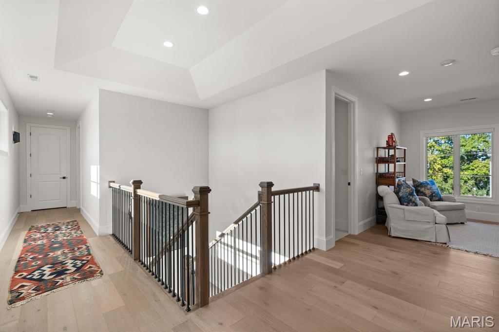 Upstairs landing with a black metal stair railing and a sitting area by the window.