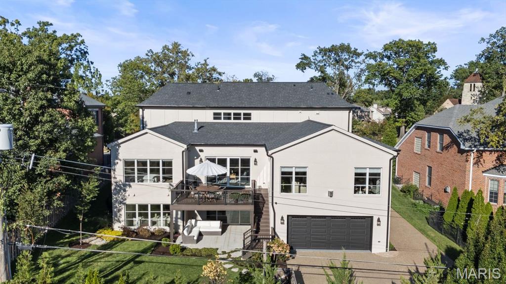 House exterior with an attached garage, elevated deck, and landscaped lawn.