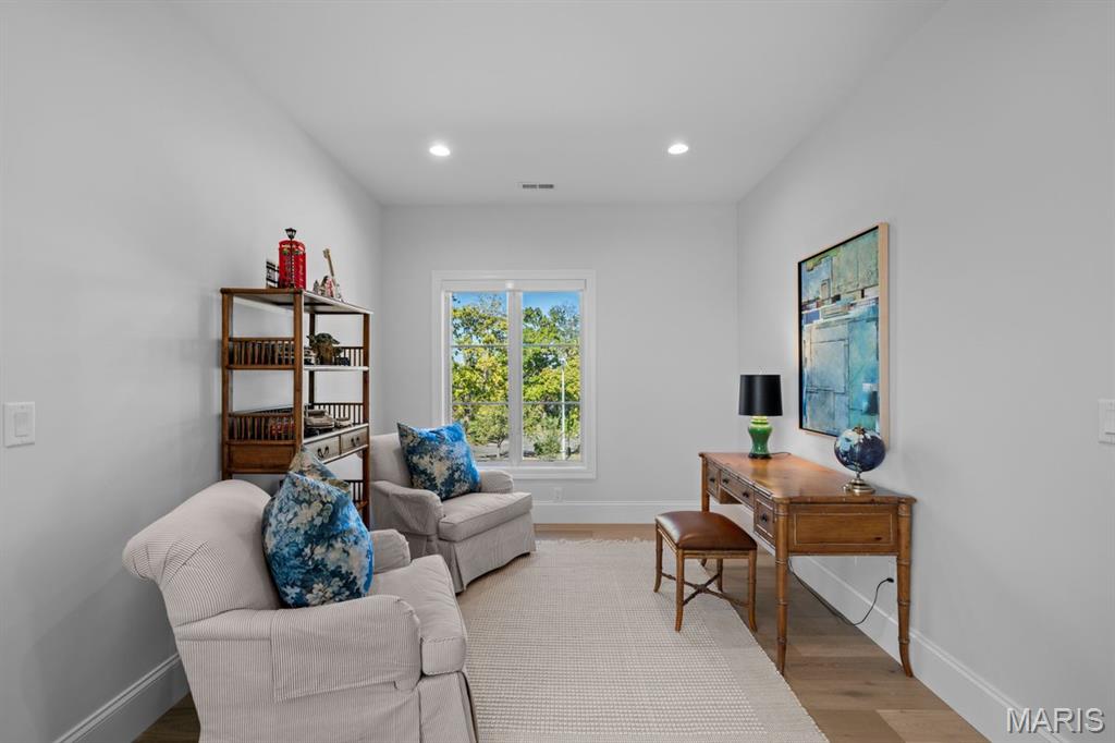 Home office with a wooden desk and bookcase beside a window overlooking trees.