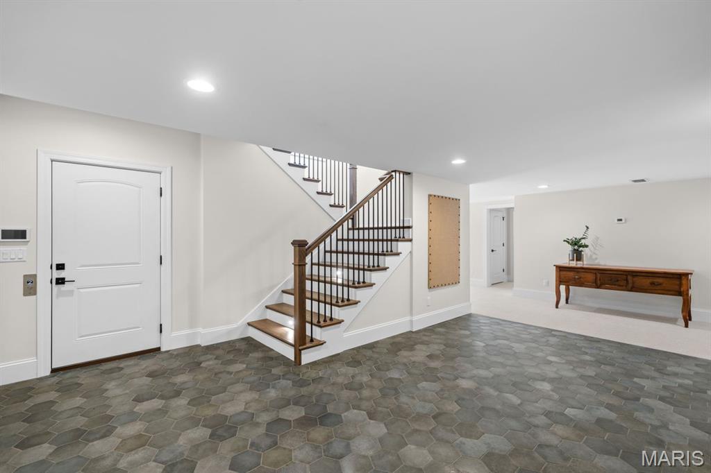 Entry hall with gray hexagonal tile, a white front door, and a wood-and-metal staircase.