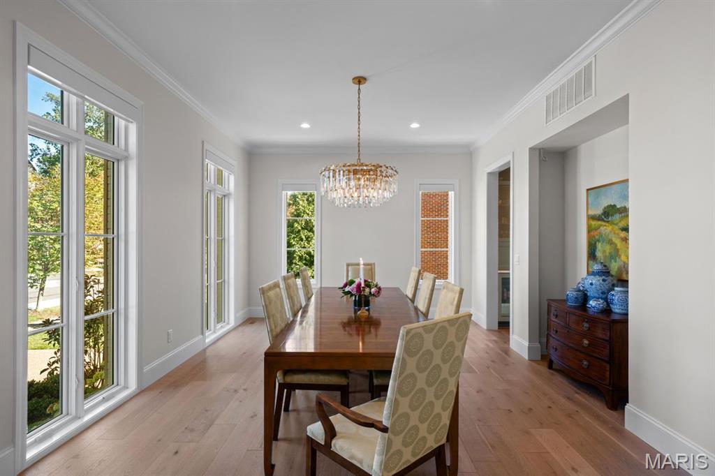 Dining room with a long wooden table, crystal chandelier, and tall windows.