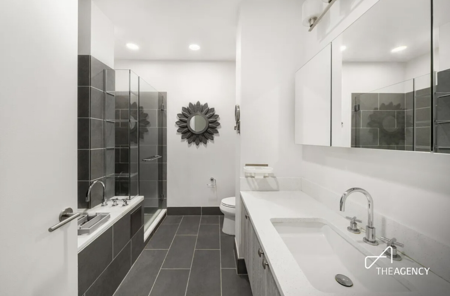 Modern bathroom with a long white vanity, mirrored cabinets, and a glass-enclosed shower.