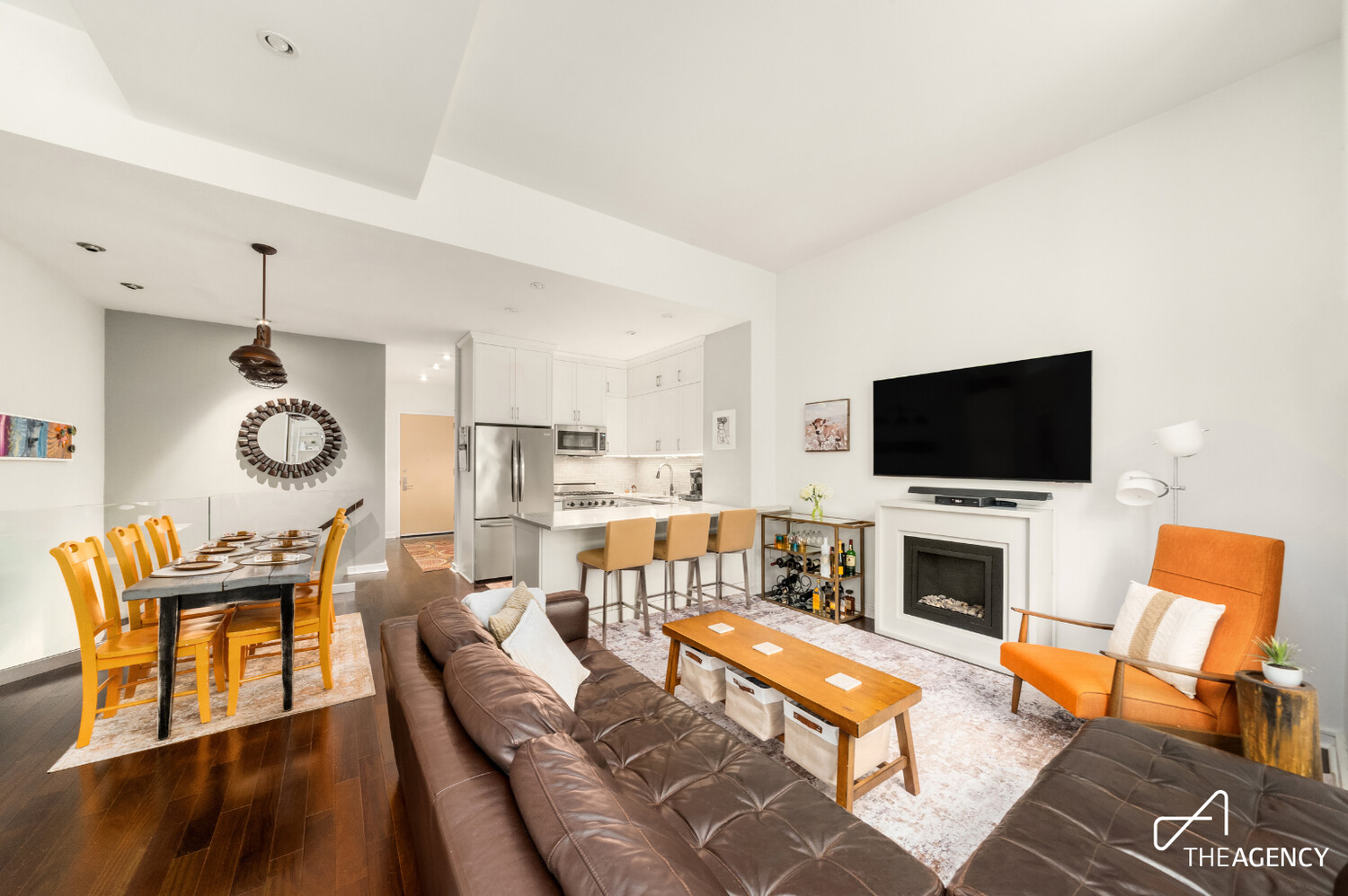 Open-plan living room with fireplace, adjoining dining area, and white kitchen.