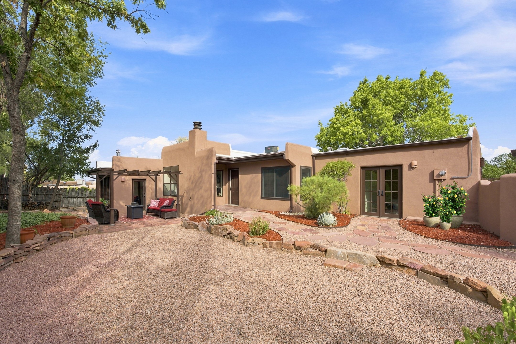 Southwestern-style home with a gravel courtyard, stone paths, desert landscaping, and shaded patio seating.