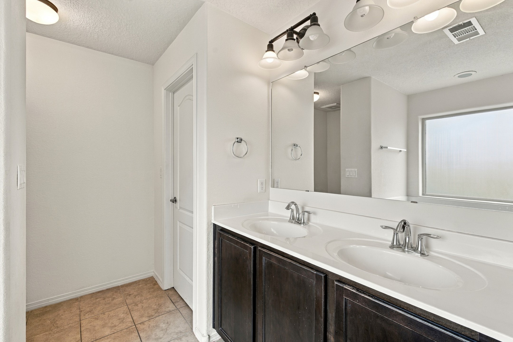 Bathroom with a dark wood double vanity, two sinks, and a large mirror.