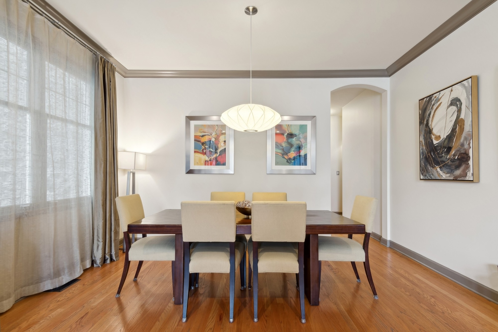 Dining room with wood table, six upholstered chairs, hardwood floors, and pendant light.