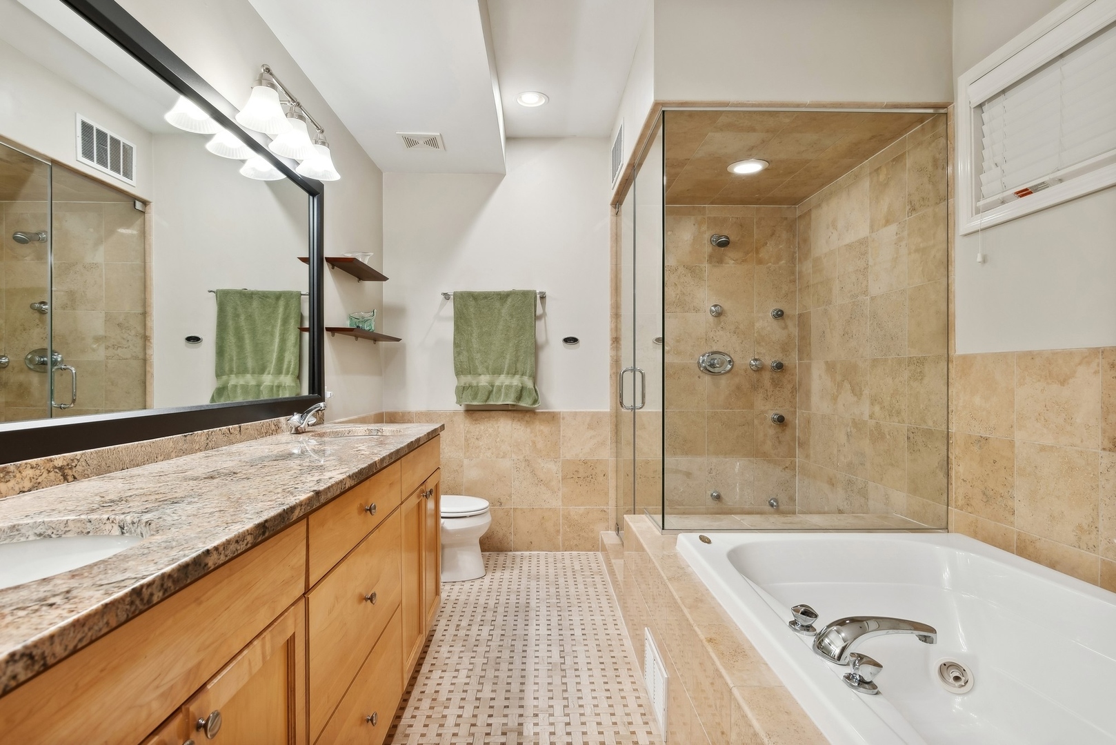 Bathroom with a wood vanity, beige-tiled glass shower, and built-in soaking tub.