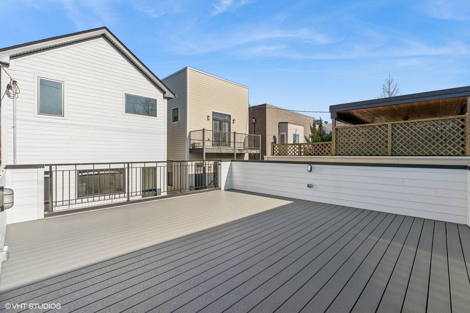 Rooftop deck with gray composite flooring, metal railings, and a covered lattice pergola.