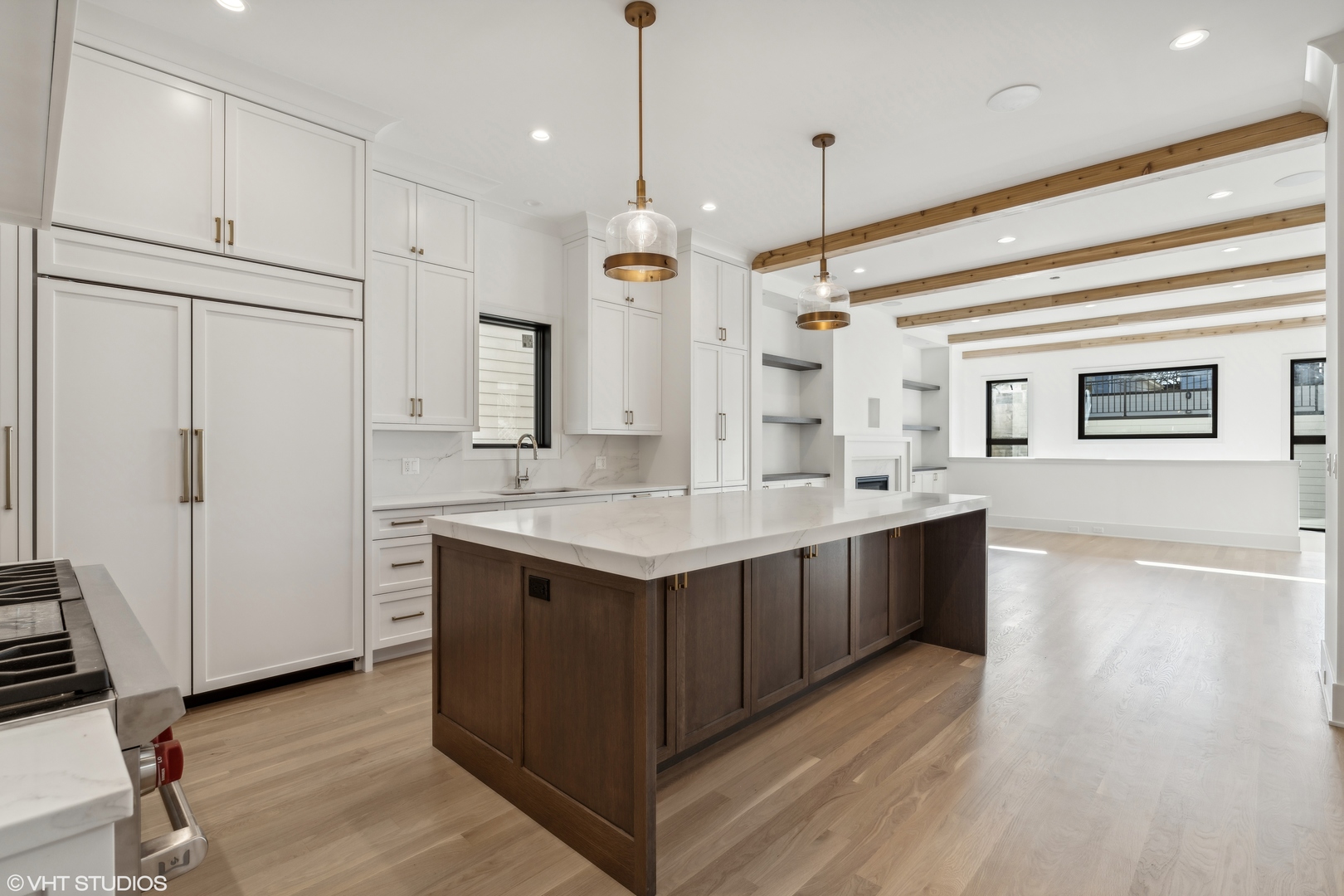 Kitchen with a large dark wood island, white cabinetry, and exposed wood ceiling beams.