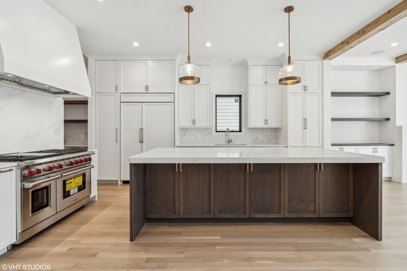 Modern kitchen with a large dark wood island, white cabinetry, and stainless steel range.