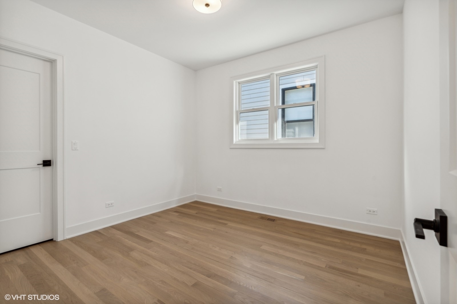Empty room with light wood floors, white walls, and a double window.