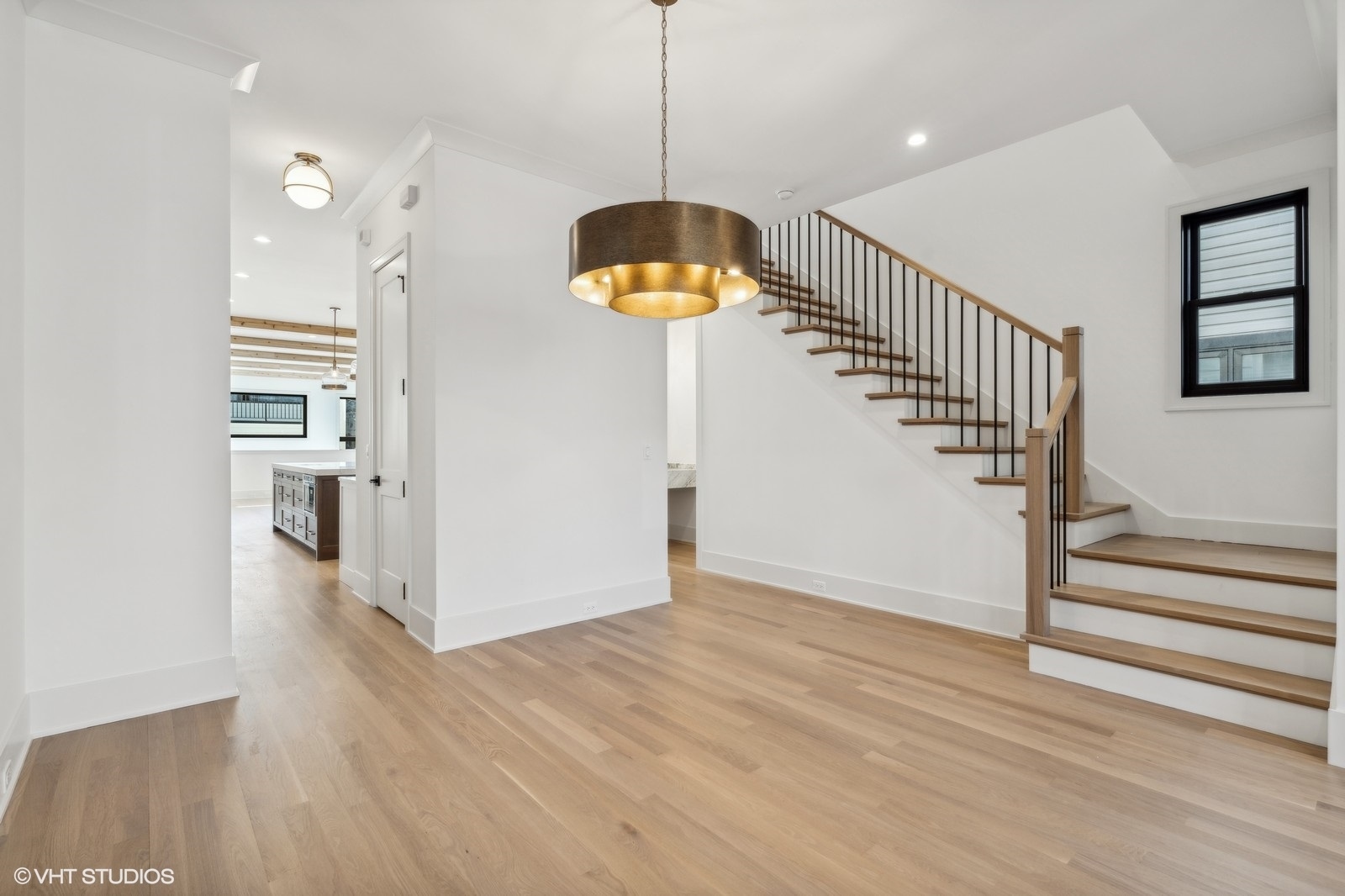 Unfurnished entry hall with hardwood floors, a wood-and-metal staircase, and a bronze pendant light.