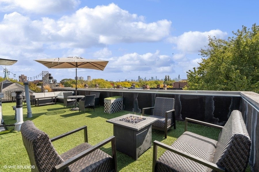 Rooftop terrace with woven seating, fire table, umbrella, and Chicago skyline views.