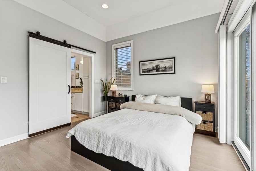 Bedroom with a large bed, sliding barn door, and floor-to-ceiling glass doors.