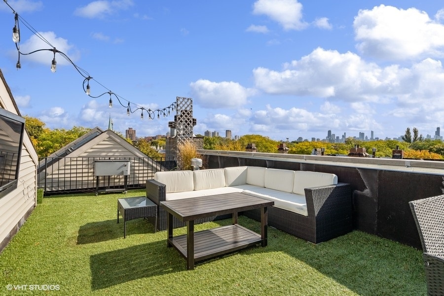 Rooftop terrace with artificial grass, wicker seating, string lights, and a view of the Chicago skyline.