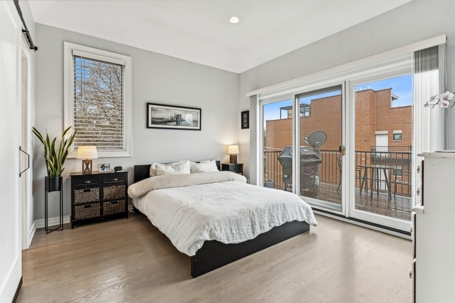 Bedroom with white bedding and sliding glass doors opening onto a rooftop terrace.